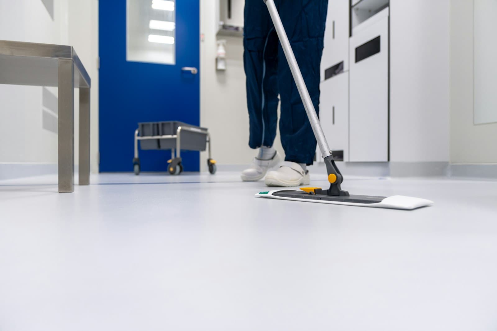 Cleaner mopping a hard floor with a flat mop